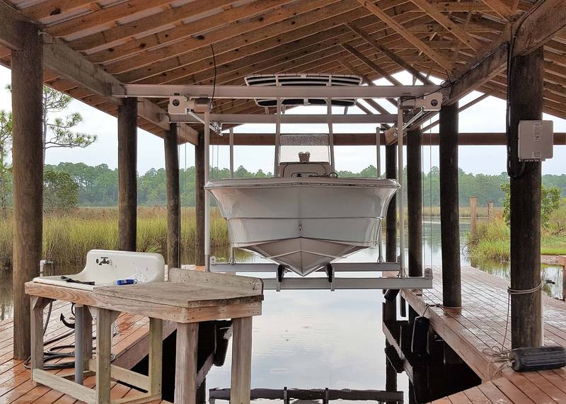 Boat raised on a lift inside a wood boathouse
