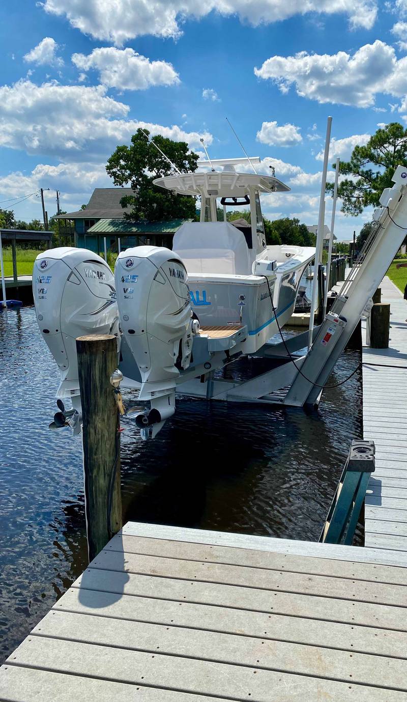 Elevator lift holding a twin-outboard boat at a dock