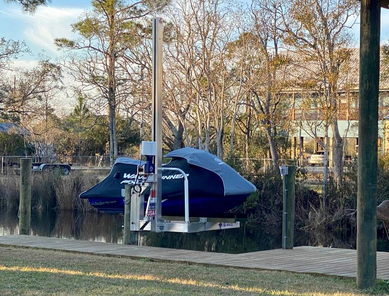 Jet ski on a lift beside a dock, marsh trees behind