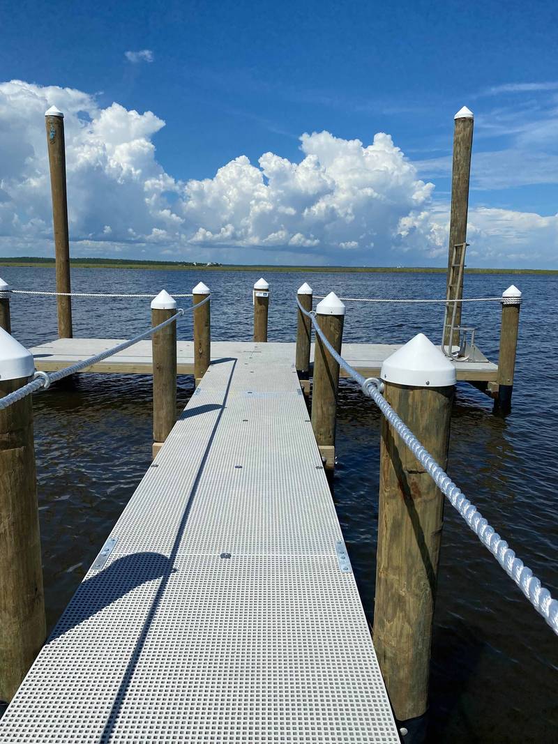 Long pier with grated decking running out to open water
