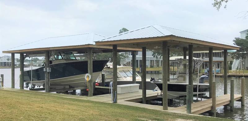 Two boathouses side by side with boats on lifts